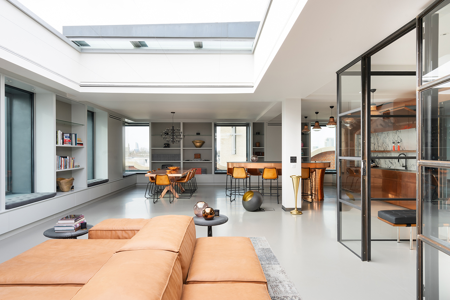 A reception room with a large skylight, internal glass doors and stylish furnishings