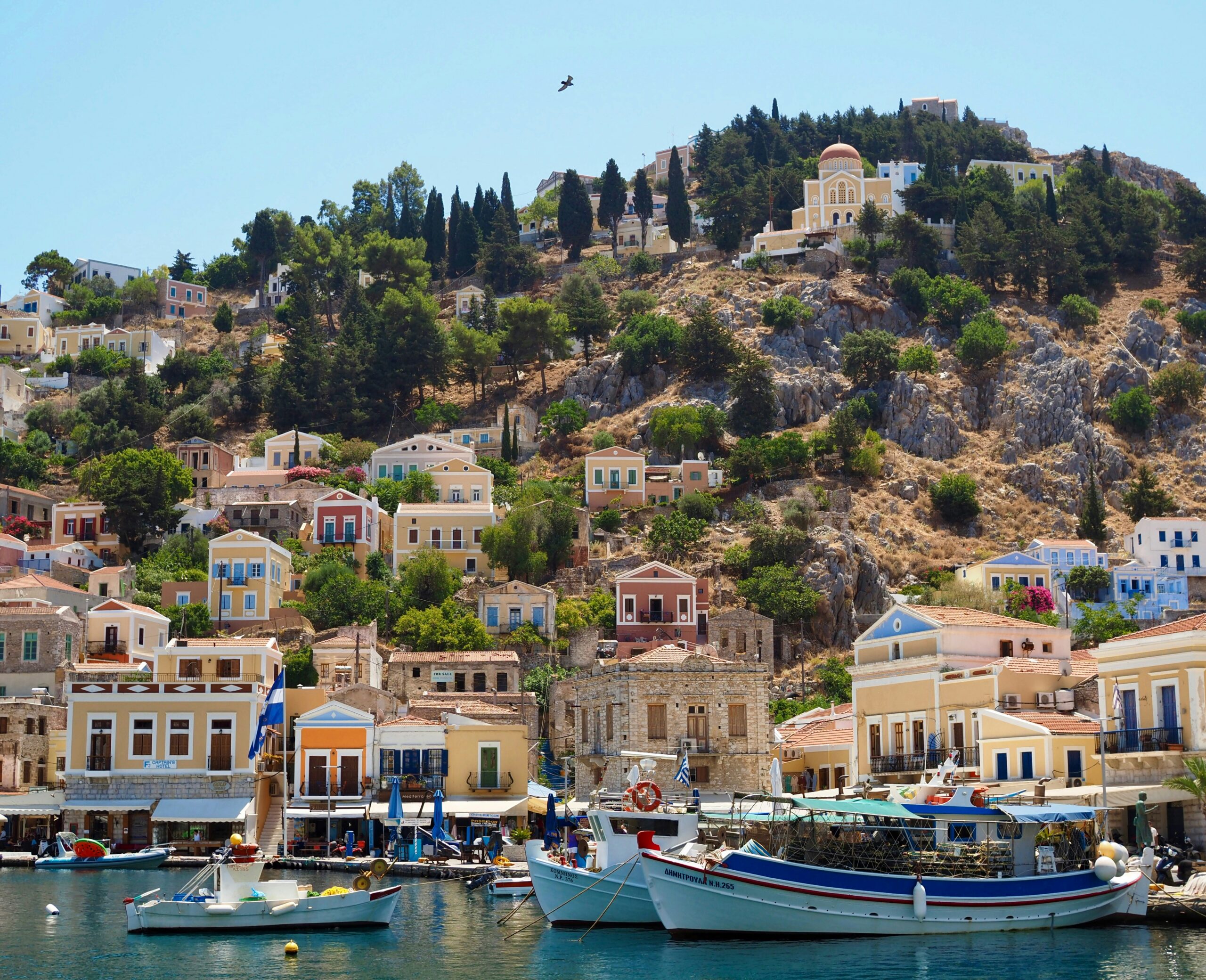 The harbour of Symi in Greece with colourful houses and boats, for Barnes International luxury real estate