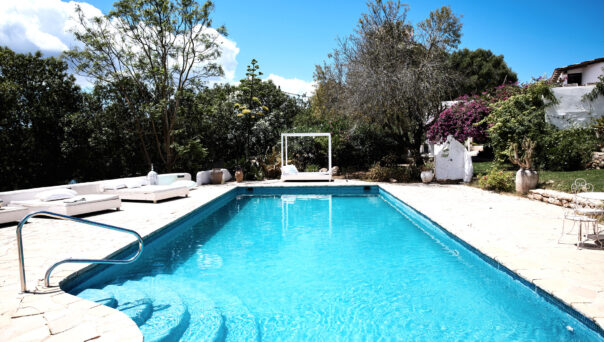 Steps lead into the azure-blue swimming pool of a luxury villa to buy near San Antonio