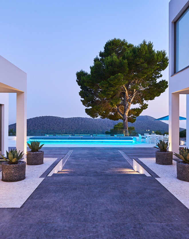 Internally lit pool casts a soft glow over the exterior of a luxury Ibiza villa at dusk
