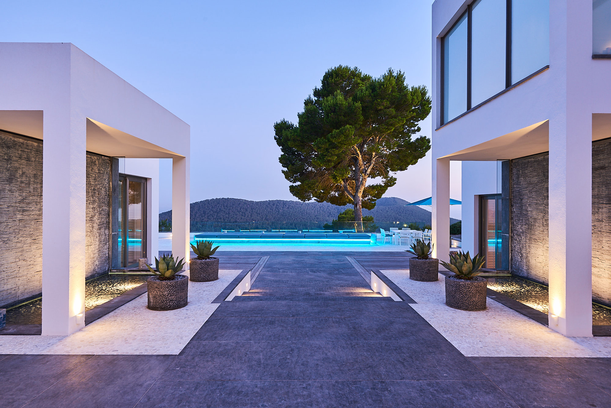 Internally lit pool casts a soft glow over the exterior of a luxury Ibiza villa at dusk