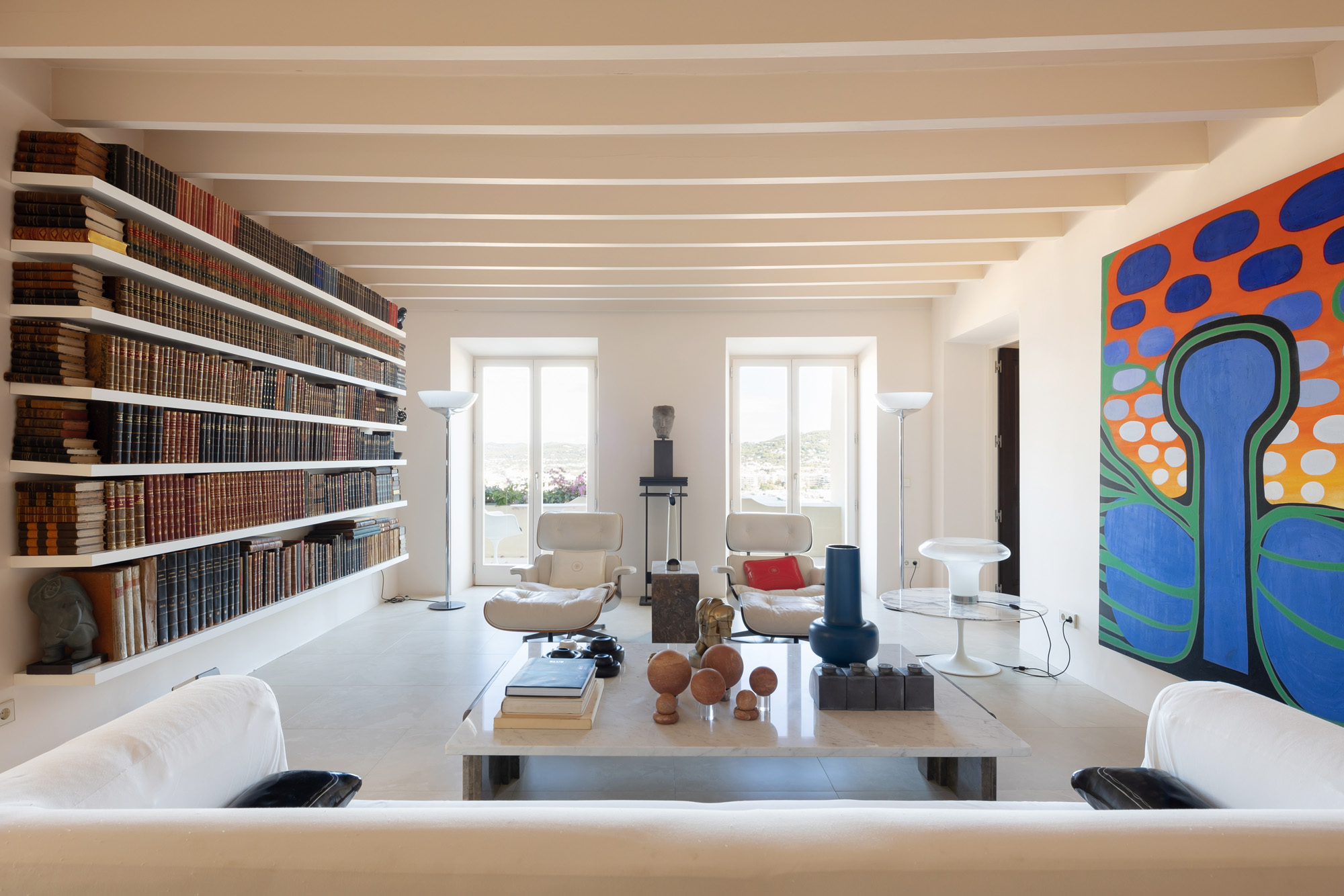 Colourful artwork and a wall of books flank the contemporary living space of a luxury townhouse for sale in Ibiza