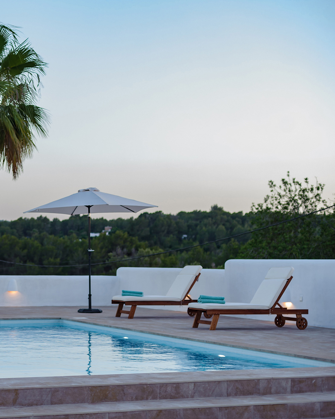 Pool furniture and the greenery of the local area surrounding a luxury holiday home in Ibiza