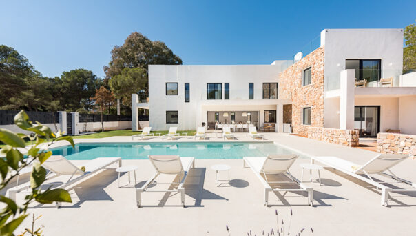 Pool furniture lounges in the sun next to a luxury villa to buy in Ibiza