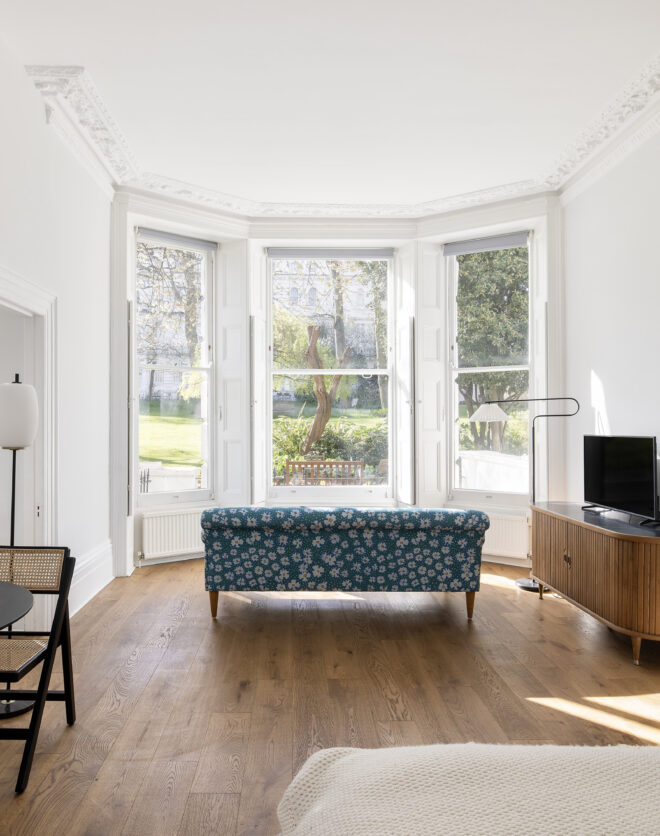 Bright open-plan living and sleeping space with a large bay window in a luxury apartment for rent in Notting Hill