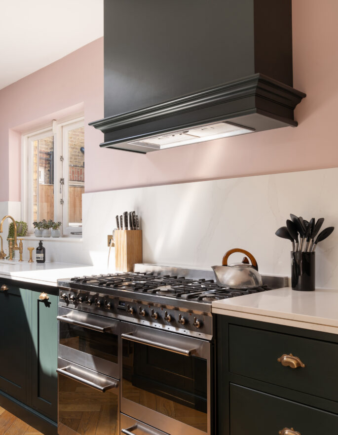A modern kitchen with a pastel pink backdrop