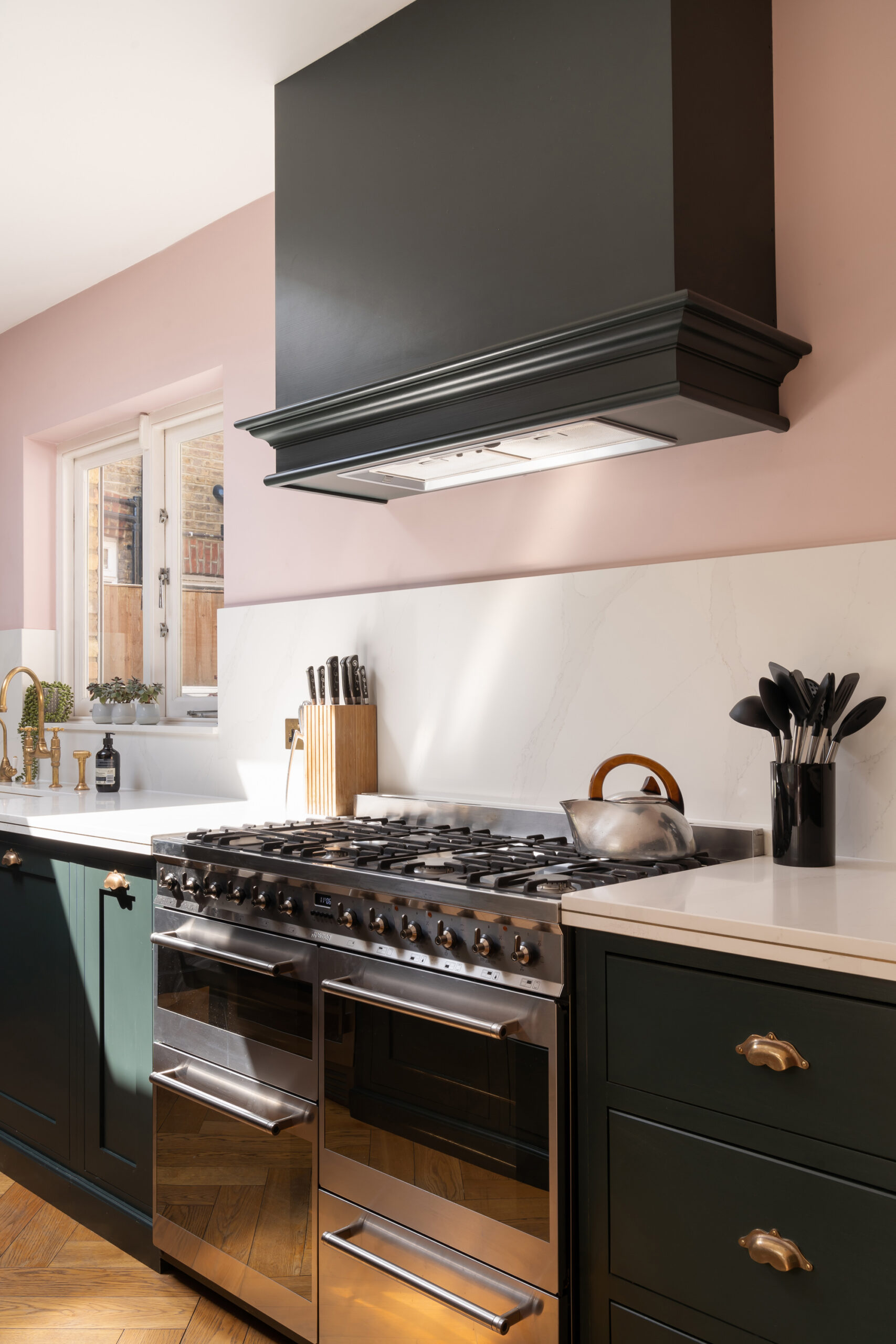 A modern kitchen with a pastel pink backdrop