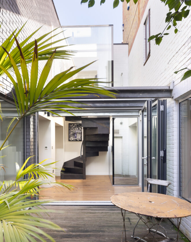 Glass doors opening to a leafy private patio of a three-bedroom duplex for sale