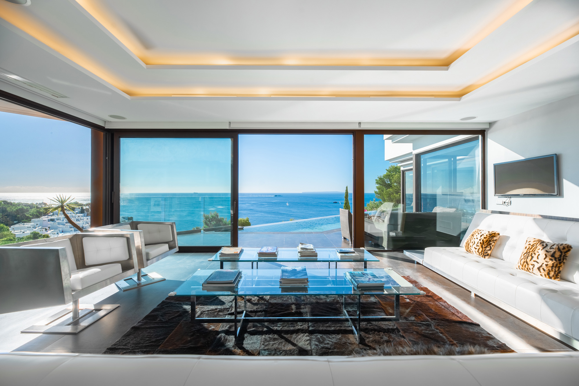Villa for sale in Ibiza with a stylish contemporary living room featuring concealed strip lighting and panoramic sea views