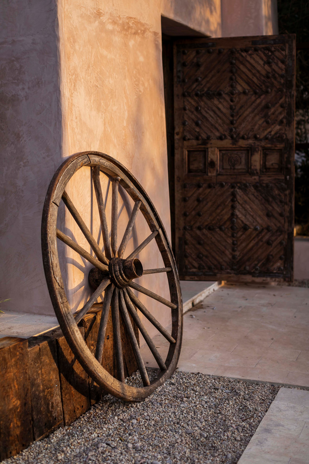 A wagon wheel leaning against the wall of a luxury villa