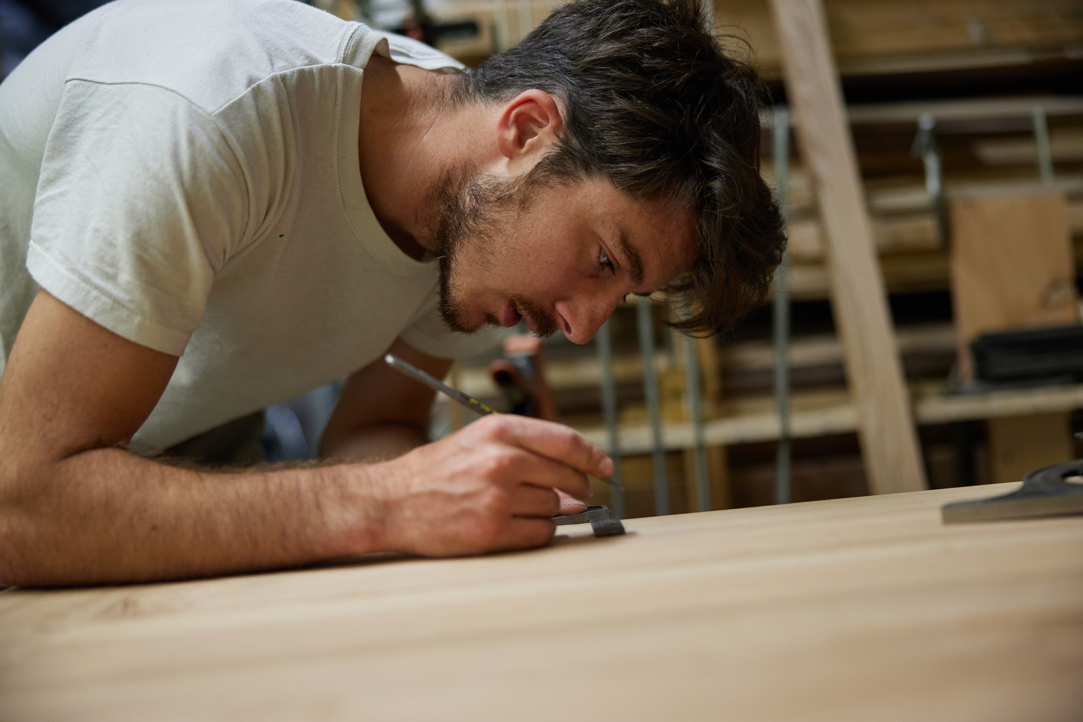 A man carefully marks a plank of wood