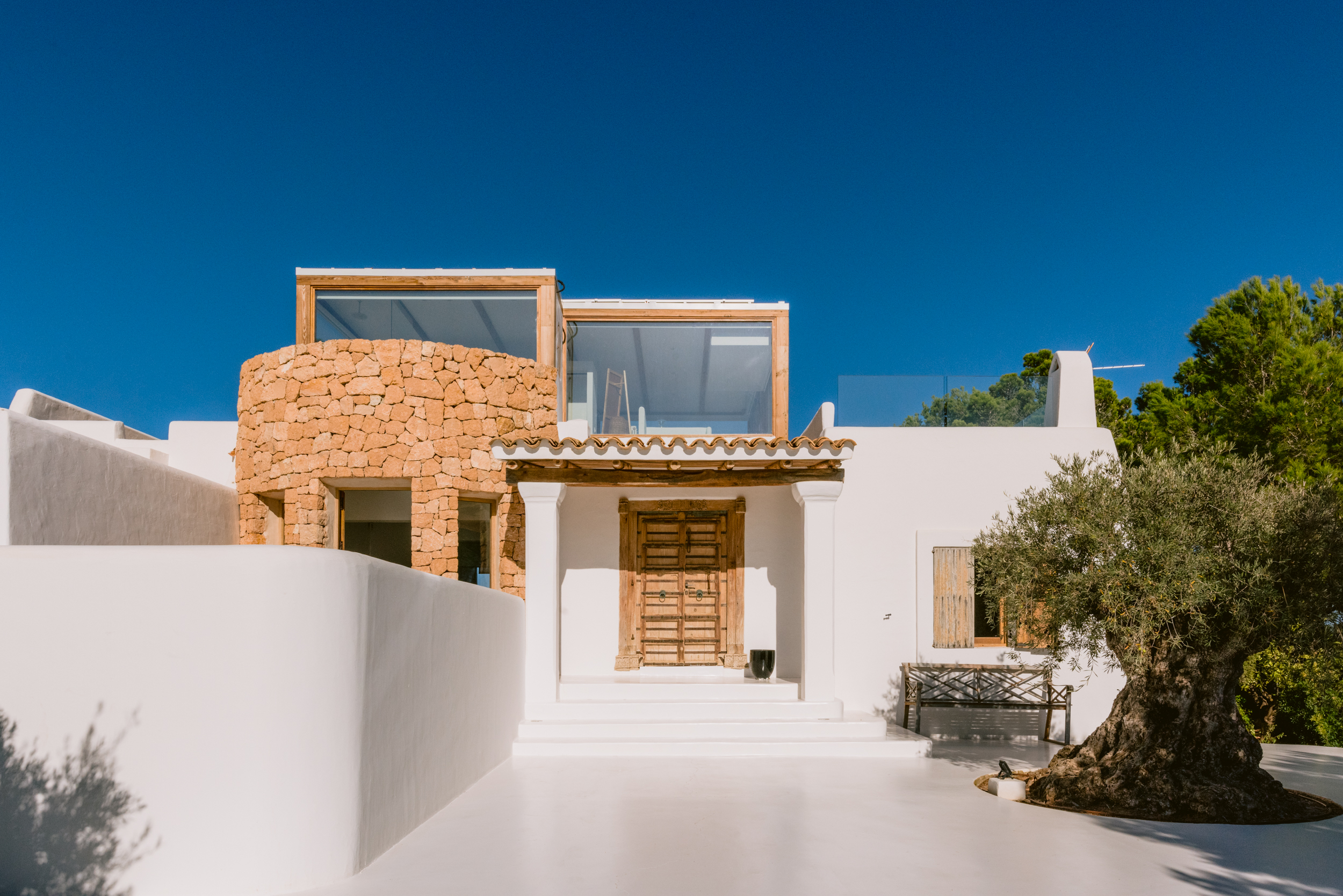 A curved honeycomb brick wall sits within the white cubic exterior of an Ibizan villa