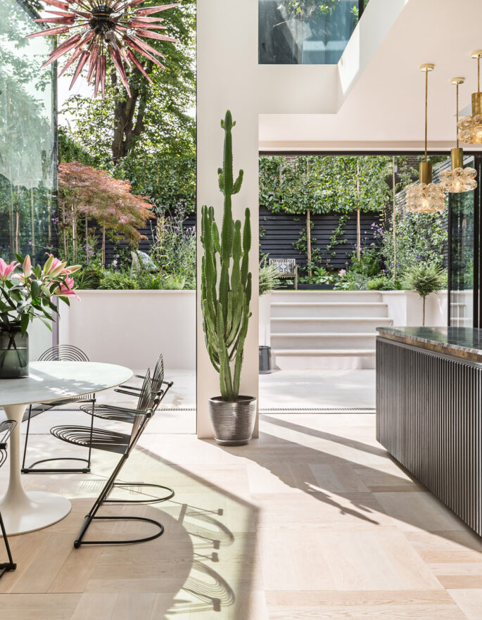 The open-plan kitchen and reception, with a striking sculptural chandelier, in a luxury rental apartment in London