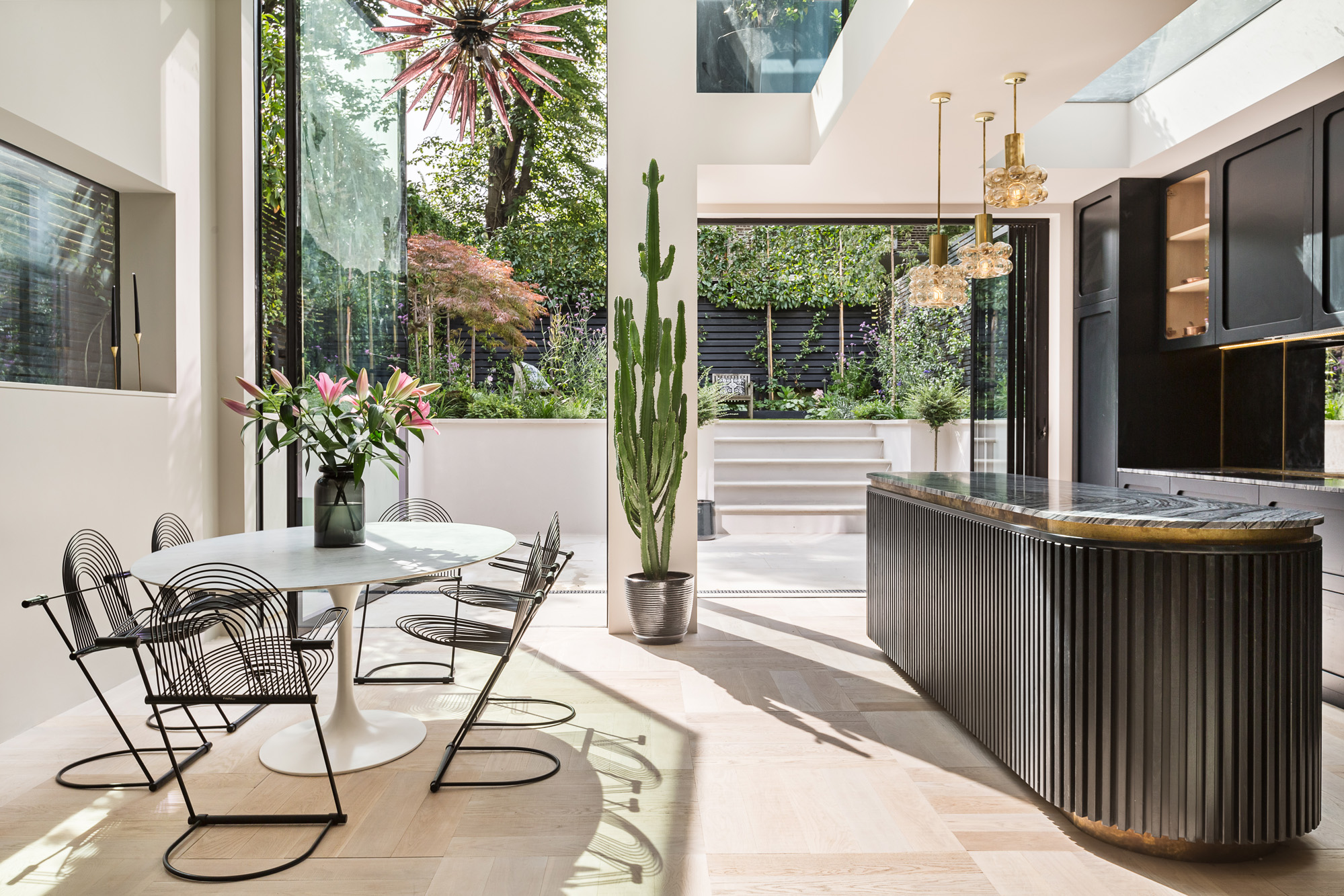 The open-plan kitchen and reception, with a striking sculptural chandelier, in a luxury rental apartment in London