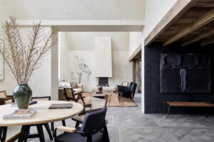 Light exposed plaster contrasts against a dark kitchen within the dramatically open-plan reception room of a luxury penthouse apartment for rent on Blenheim Crescent