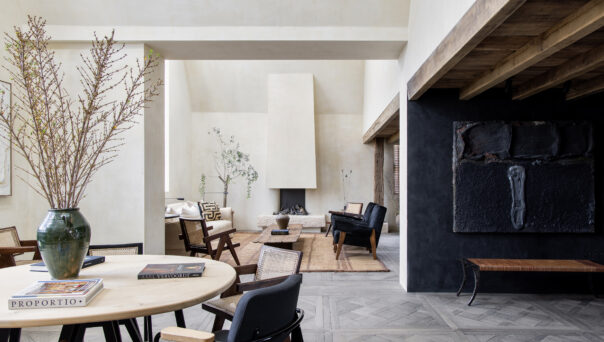 Light exposed plaster contrasts against a dark kitchen within the dramatically open-plan reception room of a luxury penthouse apartment for rent on Blenheim Crescent