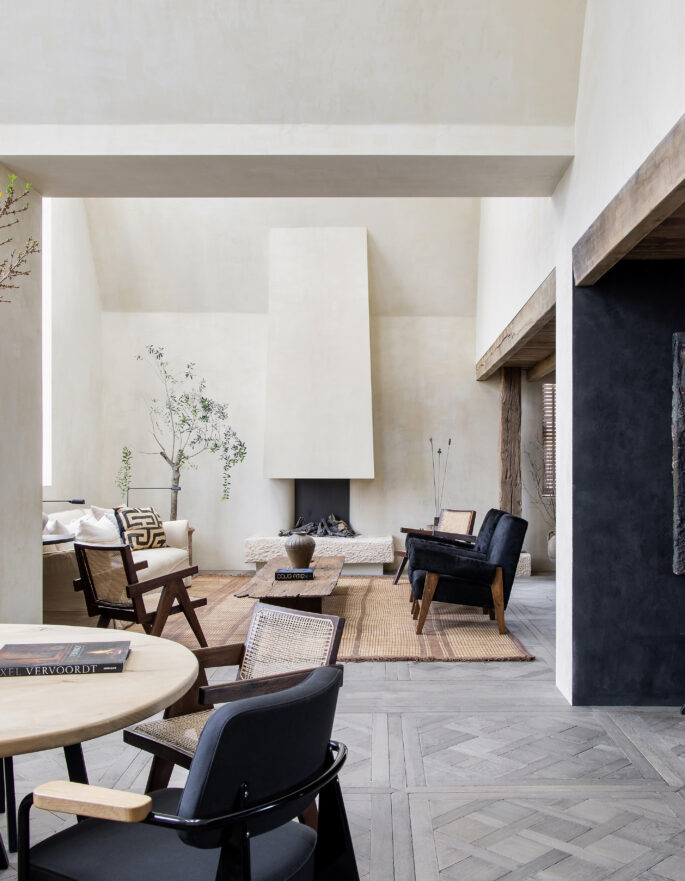 Light exposed plaster contrasts against a dark kitchen within the dramatically open-plan reception room of a luxury penthouse apartment for rent on Blenheim Crescent