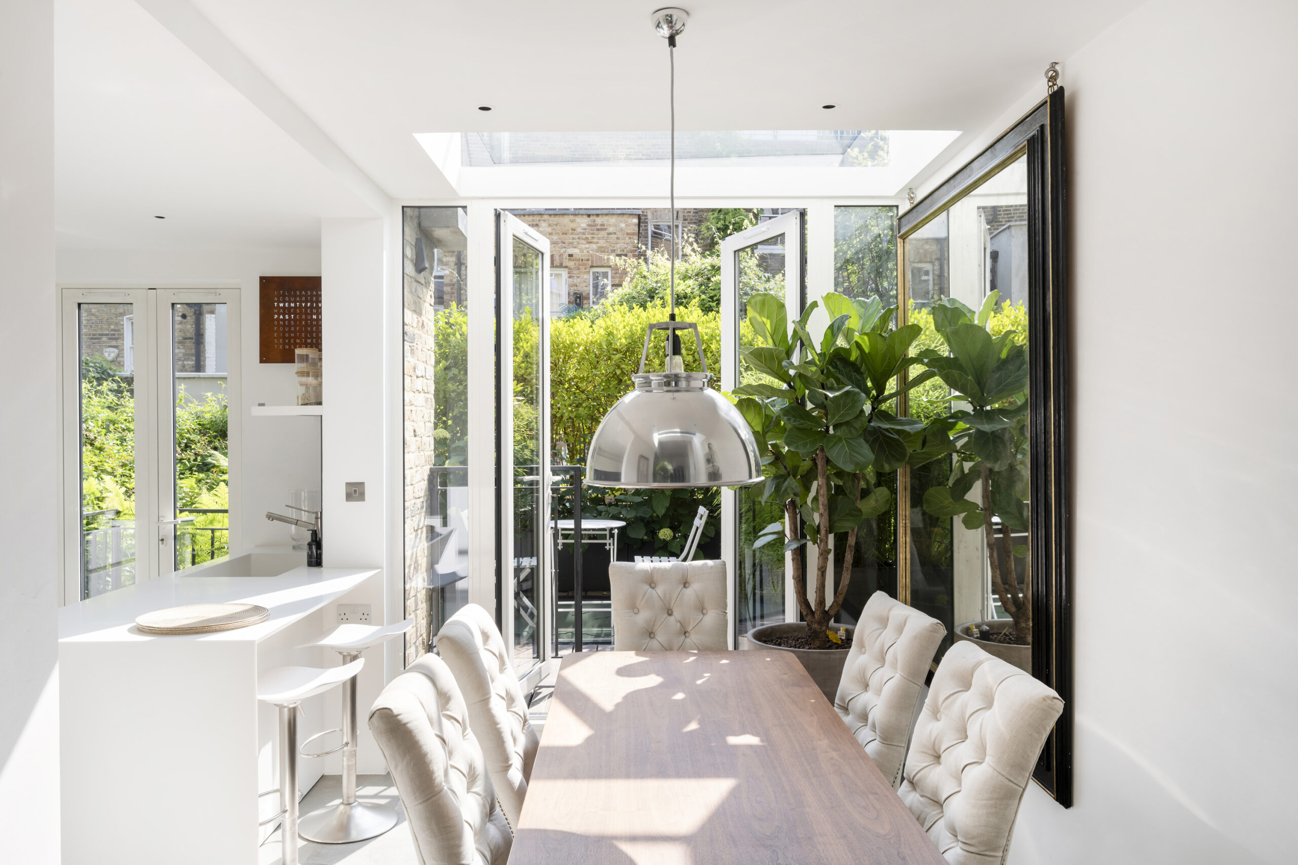 Sky-lit dining area with glass doors leading to a private patio in a luxury Notting Hill maisonette for sale