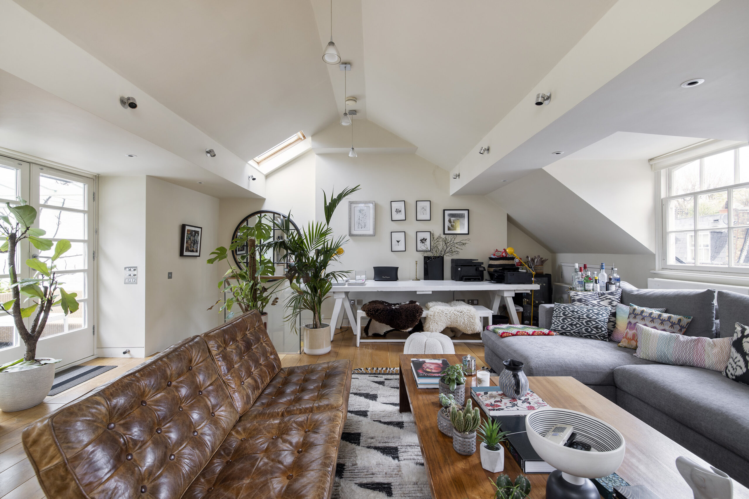 For Rent, Horbury Mews Notting Hill W11 loft style reception room with vaulted ceiling, house plants and leather sofas