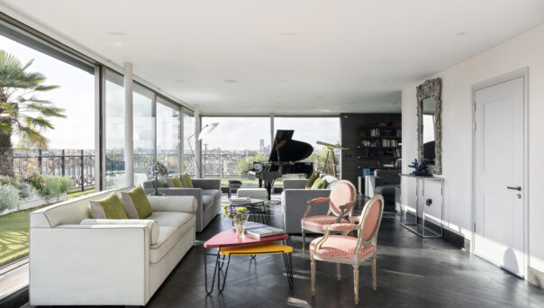 Bright open-plan living space with wraparound glazing leading to a roof terrace in a penthouse apartment for sale on Westbourne Grove