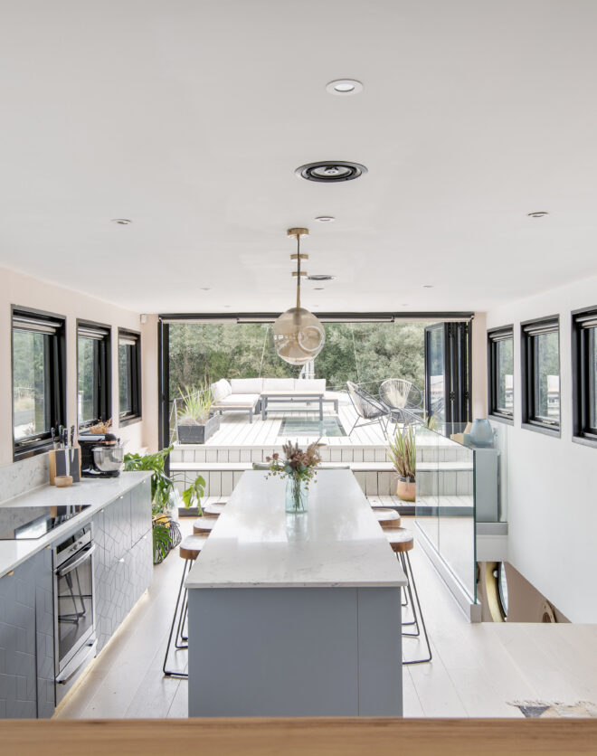 Bright luxury kitchen with island and bi-folding glass doors in a house boat for sale
