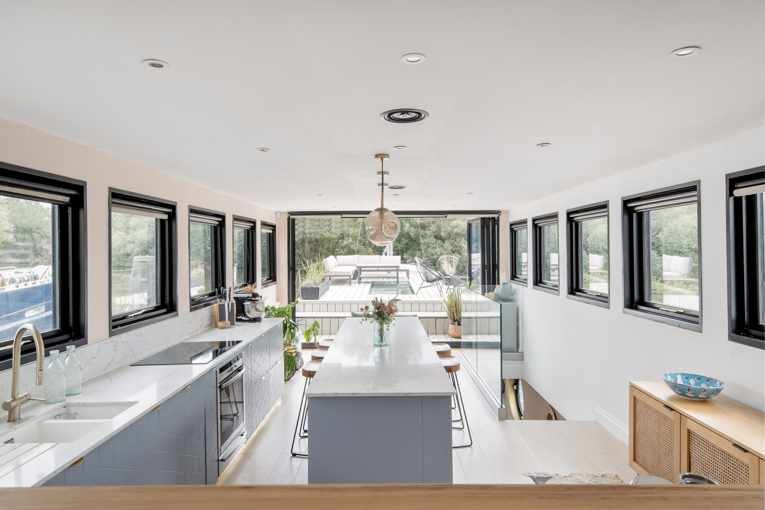 Bright luxury kitchen with island and bi-folding glass doors in a house boat for sale