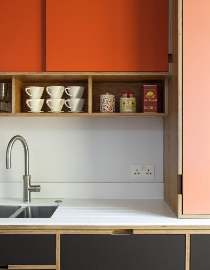 Orange cupboards and sink by Uncommon Projects