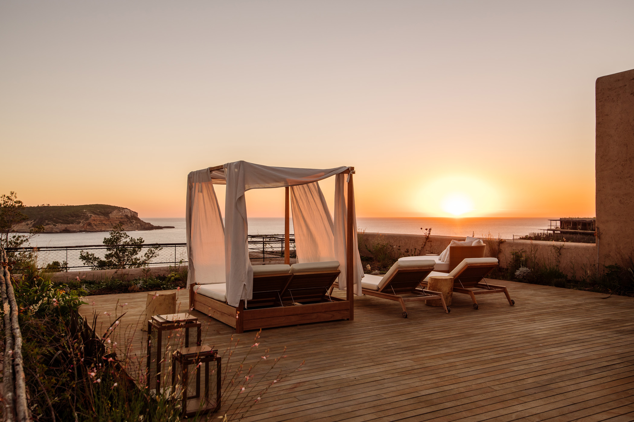 Day bed of a luxury rental villa in Ibiza overlooking the sun as it dips into the ocean