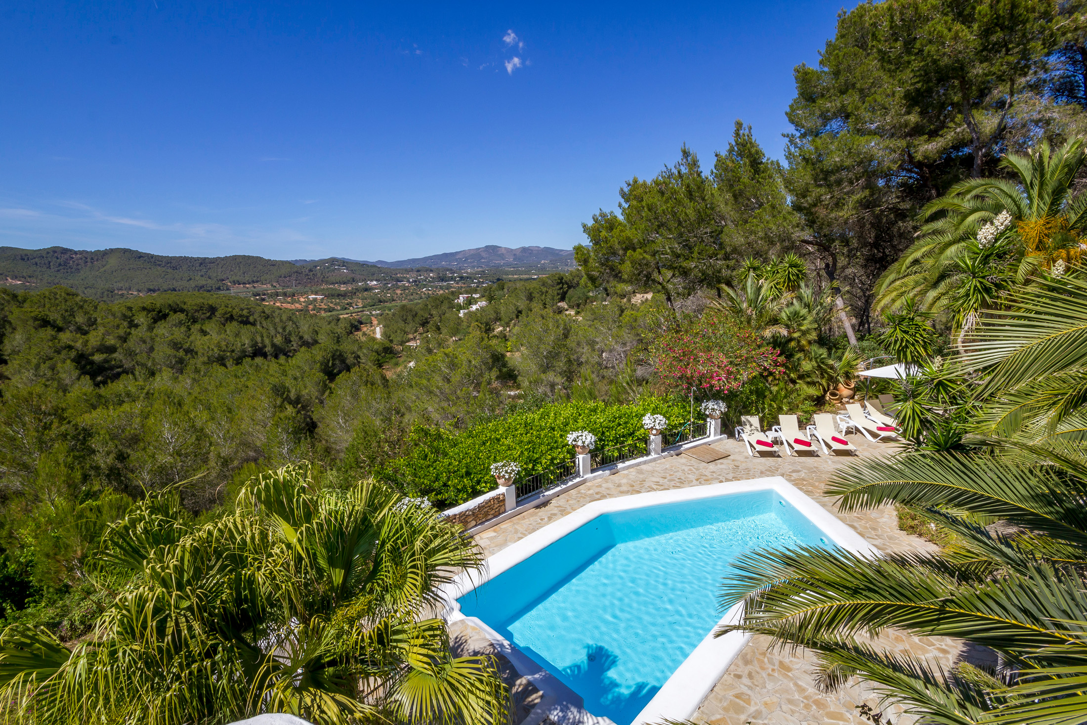 Angular pool of a luxury villa for sale in Ibiza overlooks a verdant valley